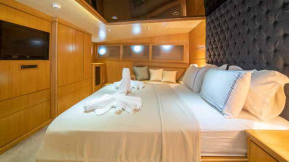 A luxurious cabin on a traditional Turkish gulet, equipped with a large, comfortable bed and stylish wood panelling.