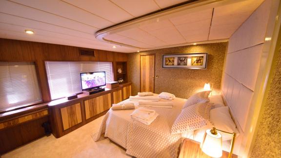 The bedroom of Simay F yacht features a large bed, modern decor, and a TV.