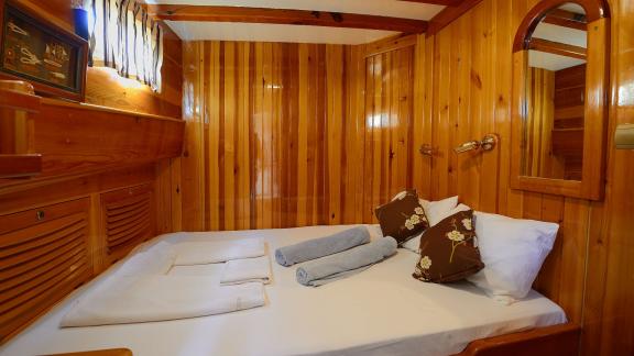 Warm wood cabin of Gulet Xenos 2 in Bodrum with a comfortable double bed and stylish details.