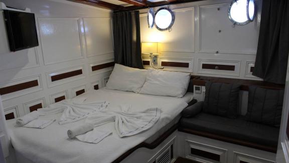 Moderne Kabine der Grande Mare mit Doppelbett, TV und Sitzbereich. Perfekt für luxuriöse und entspannende Yachtcharter i