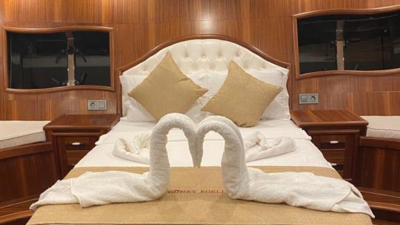 Luxurious cabin with a double bed, decorative swan-shaped towels, and wooden furniture.