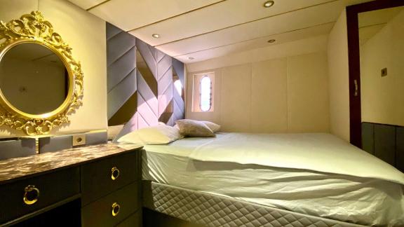 The modern bedroom on Vedo B yacht features a luxurious mirror and a comfortable bed.