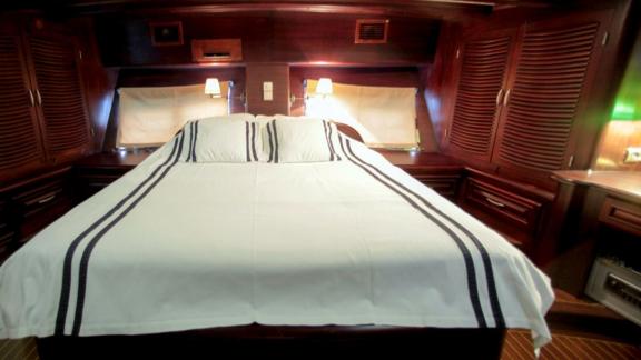 A comfortable cabin on board the Gulet Dulcinea with a large bed and stylish wood panelling.