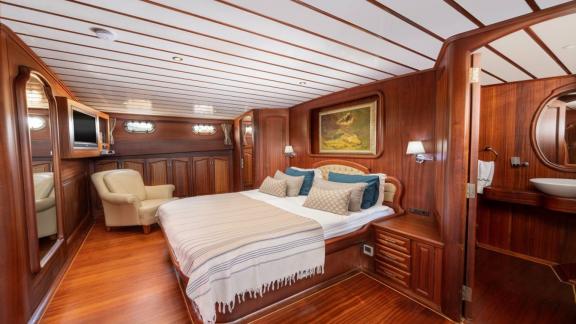 Spacious bedroom on a boat with double bed, mirror, desk and wooden interior.