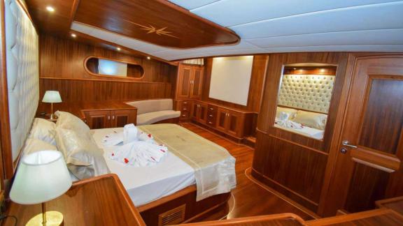 Spacious cabin with a stylish bed and cozy seating area, perfect for relaxing cruises on the Gulet Baba Can.