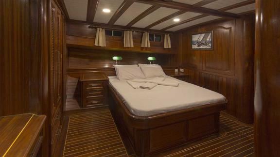 Comfortable cabin with a large bed, wood panelling.