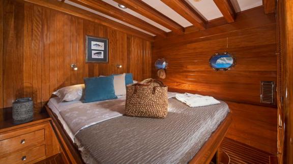 A cosy double cabin on board the Flas VII, with wooden panelling and small porthole windows for a nautical atmosphere.