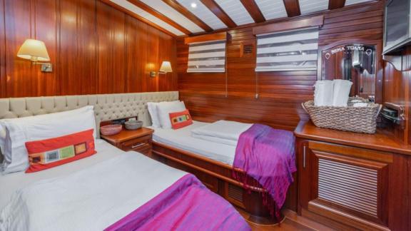 A cosy twin cabin on a luxurious gulet with wooden walls, comfortable beds and elegant accents.