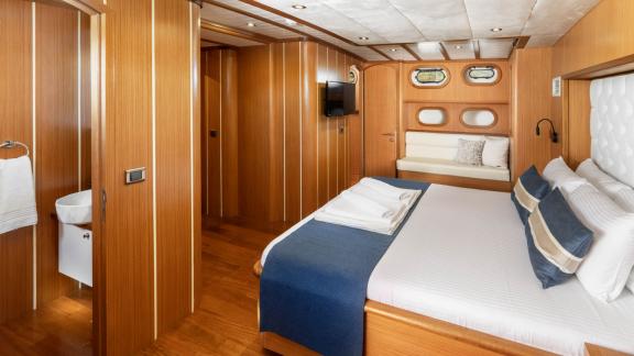 Bright and spacious cabin of the gulet Gozdem The One with large bed, seating area, TV and wood panelling.