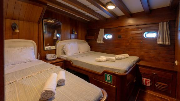 Comfortable twin cabin of the Serenad yacht with two single beds and elegant wood decor.