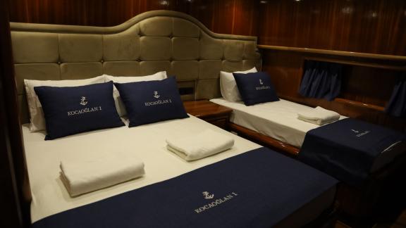 Kabine mit einem Doppel- und einem Einzelbett auf einer Yacht.
