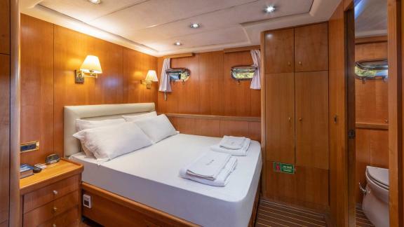 A comfortable double cabin on a Bodrum gulet, equipped with a large bed, wood panelling and soft lighting.