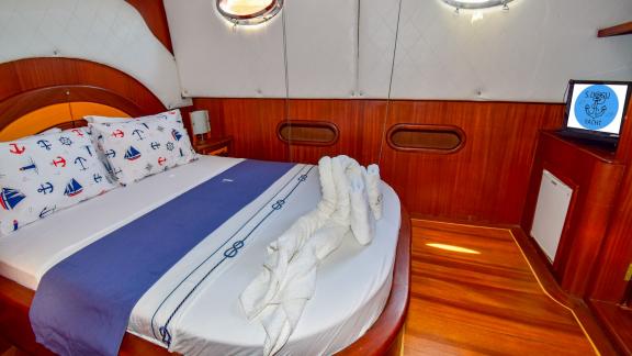 Kabine auf einer Segelyacht mit einem dekorativ gestalteten Bett und eleganten Holzmöbeln.