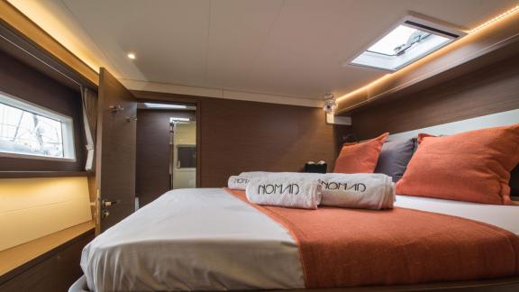 Luxuriöses Schlafzimmer im Katamaran Nomad mit orangefarbenen Details und einladender Atmosphäre.