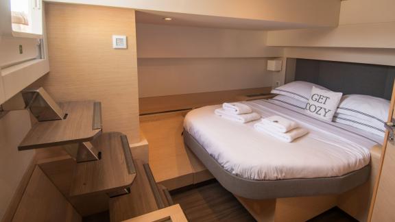 Comfortable, compact bedroom on the Serenissima catamaran with practical shelving.