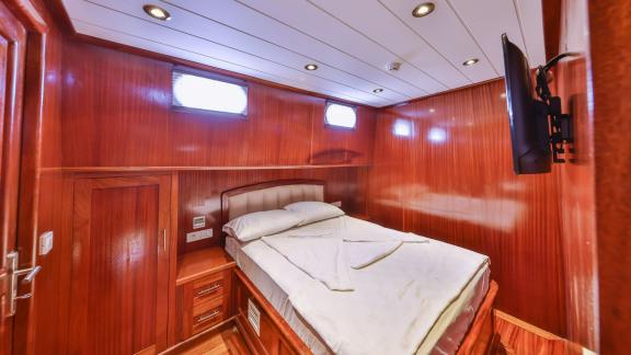 A cozy cabin with a double bed and wooden paneling on the Gulet Kasapoglu 6.