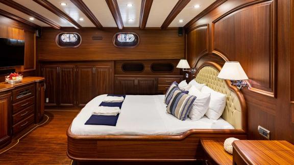 Spacious cabin with elegant wooden interior, luxurious double bed, wardrobes and porthole windows.