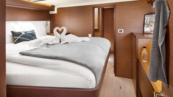 Modern cabin in Emerald Gemini with a double bed, decorative towels, and passage to another room.