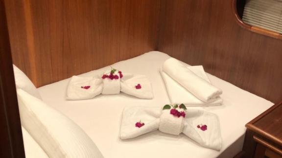 Double bed in a cabin, decorated with towels and flower petals.