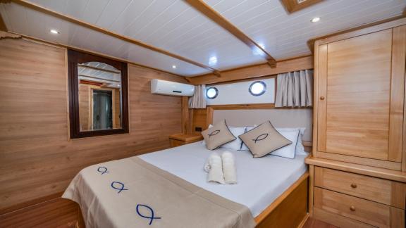 Ein stilvolles Schlafzimmer auf der Gulet-Yacht Amazon Solo mit Doppelbett und Holzmöbeln.