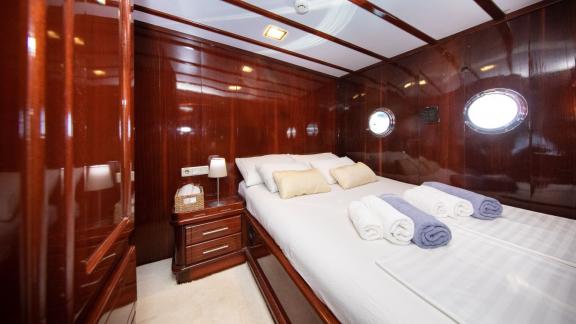 Stylish cabin of the Gulet Vivere with elegant wooden furnishings, cosy bed and soft towels.