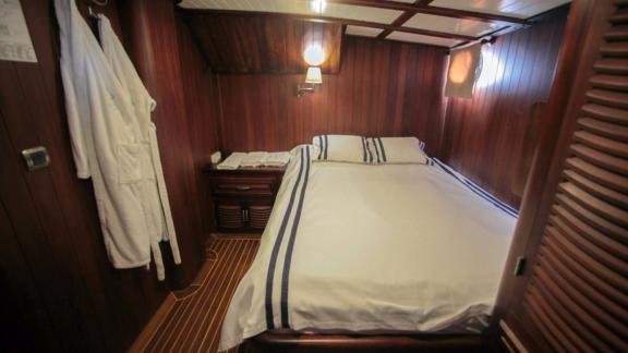 A cosy cabin on board the Gulet Dulcinea with a comfortable bed and elegant wood panelling.