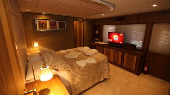 The bedroom of Simay F yacht features a large bed, cozy decor, and a TV.