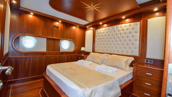 Luxurious cabin with padded headboard and elegant wooden furniture on the Gulet Baba Can.