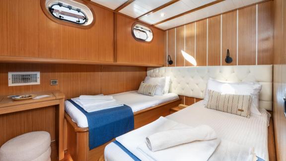 Double cabin of the gulet Gozdem The One with two single beds, wood panelling and bright, stylish accents.