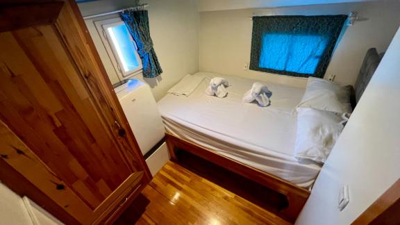 Bright cabin on Gulet Simi with a double bed, two windows, and wood finish, perfect for restful nights.