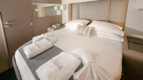 Elegantes Gästezimmer auf Katamaran Alonia mit Doppelbett und personalisierten Handtüchern.