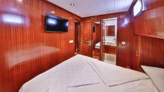 A comfortable cabin on the Gulet Kasapoglu 6 with a double bed, TV, and en-suite bathroom.