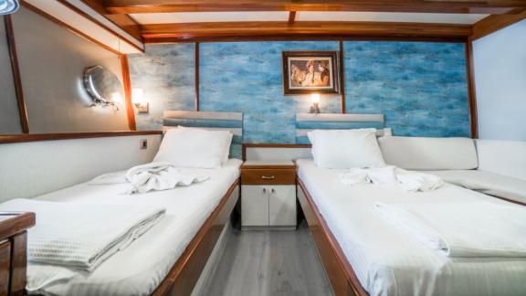 Cabin with two single beds, blue wall decoration, bedside table and maritime details.