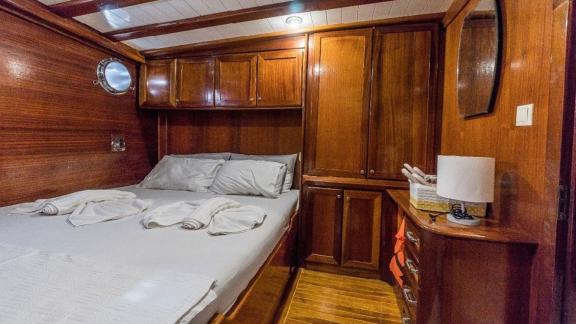 Cozy double cabin with wooden cabinets and bed on the Gulet Optimist in Bodrum.