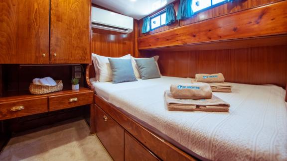 The comfortable cabin on Gulet Rüya features a cozy bed and ample storage in an elegant wooden design.