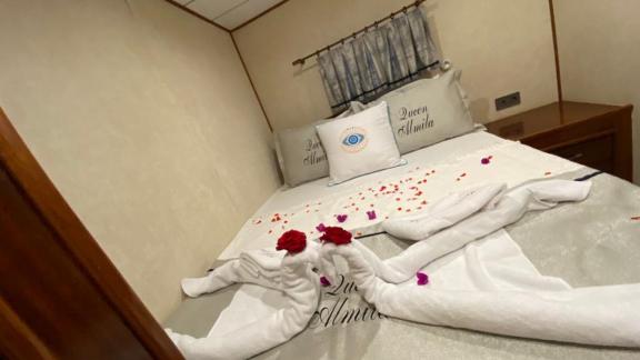 Tasteful towel art and rose petals in a cozy cabin on the Queen Almila gulet.