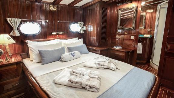 Elegant cabin on the gulet Entre Cielos with large bed, maritime décor and en-suite bathroom.