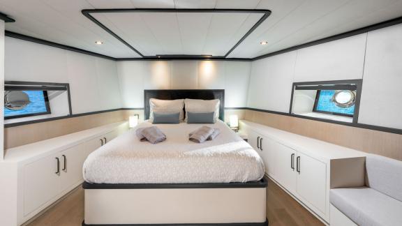 Modern and stylish bedroom; equipped with a large bed, cupboards, and panoramic view windows.