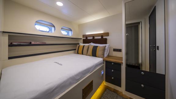 Cabin with double bed, porthole windows, and mirror on Gulet Golden Glory.