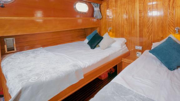 A bright twin cabin on board the Flas VII, with warm wooden décor and comfortable beds.