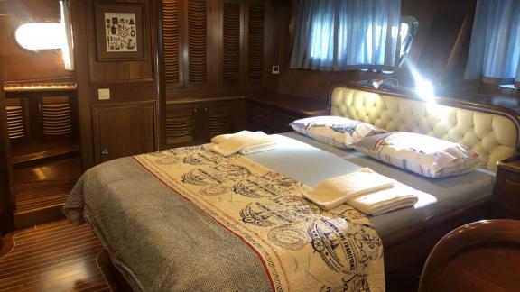 The Enderim A cabin has a double bed with an elegant bedspread and window.