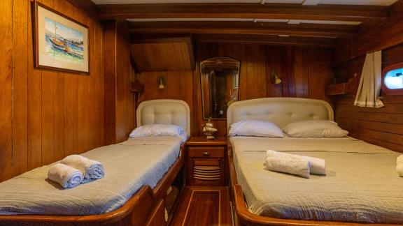 Stylish twin bed cabin on the Serenad yacht with two single beds and classic wood decor.