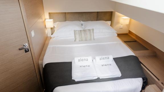 Compact cabin with double bed, elegant lighting, and fresh towels.