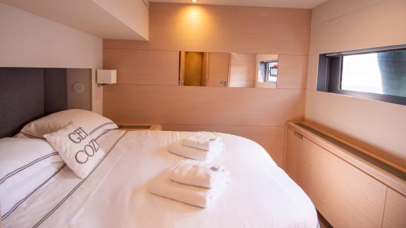 Cozy bedroom with a window on the Serenissima catamaran that lets in plenty of natural light.