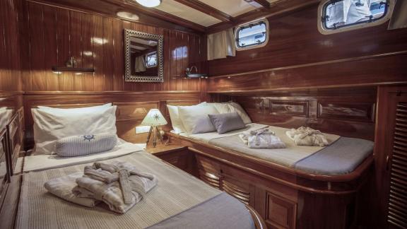 Cosy double cabin on the gulet Entre Cielos with two beds, fine wooden furnishings and maritime décor.