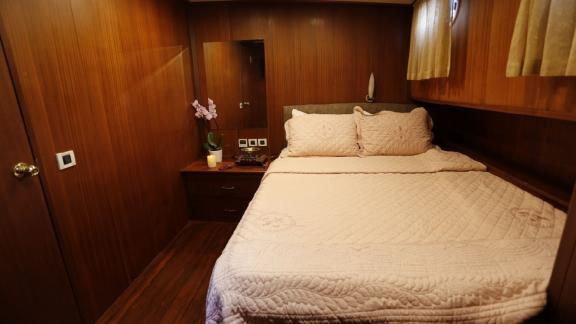 Comfortable bedroom with a double bed and elegant wood paneling on Gulet İlknur Sultan.