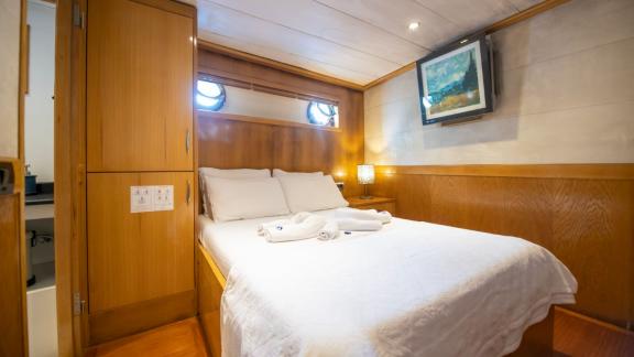 Cabin with double bed, two portholes, and a painting on Gulet Cemre Mila.