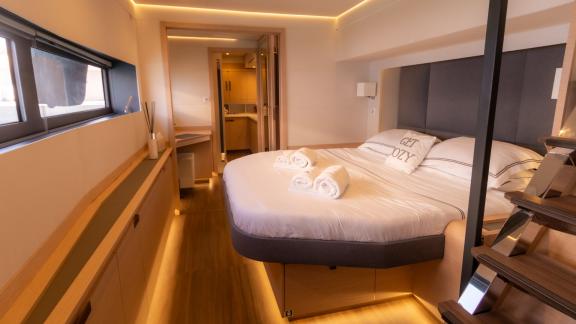 Stylish and cozy bedroom on the Serenissima catamaran with lighting and sea view.