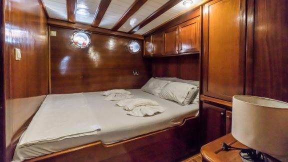 Compact double cabin with wooden interior and portholes on the Gulet Optimist in Bodrum.