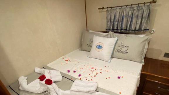 Cozy cabin on the Queen Almila gulet with decorative towels and flower petals.